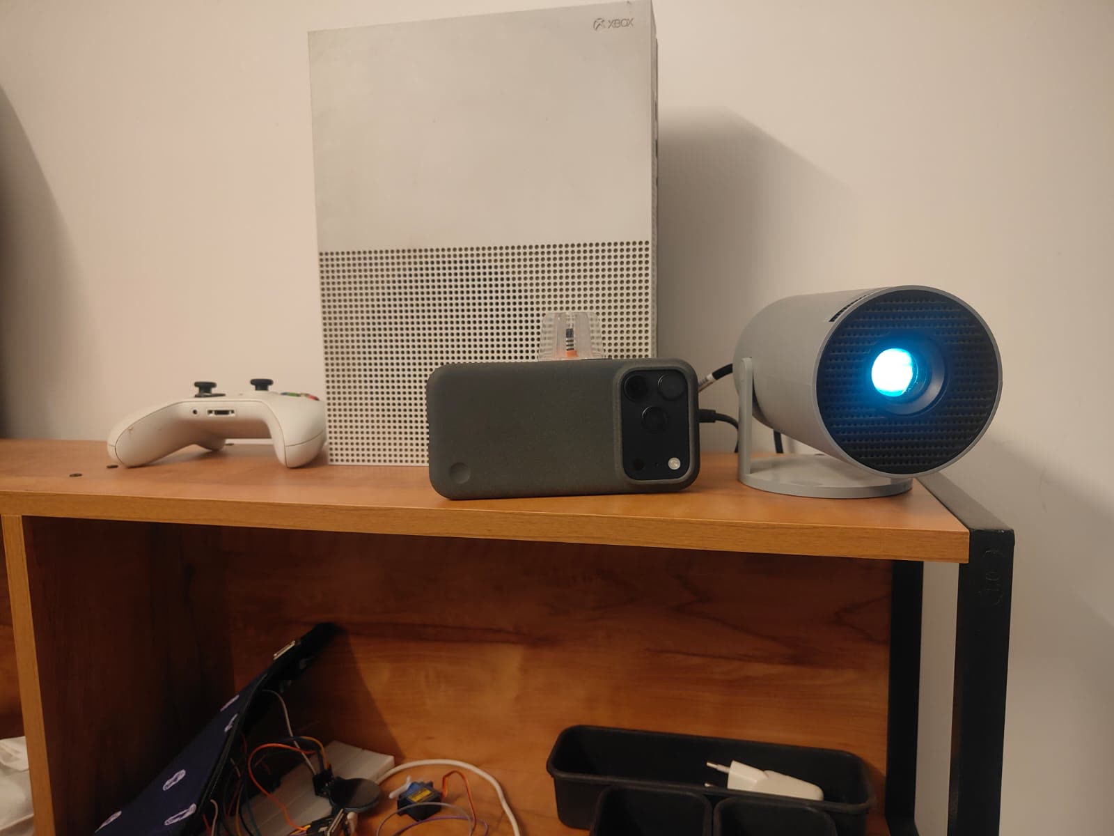 An iPhone and a small projector side by side on a shelf